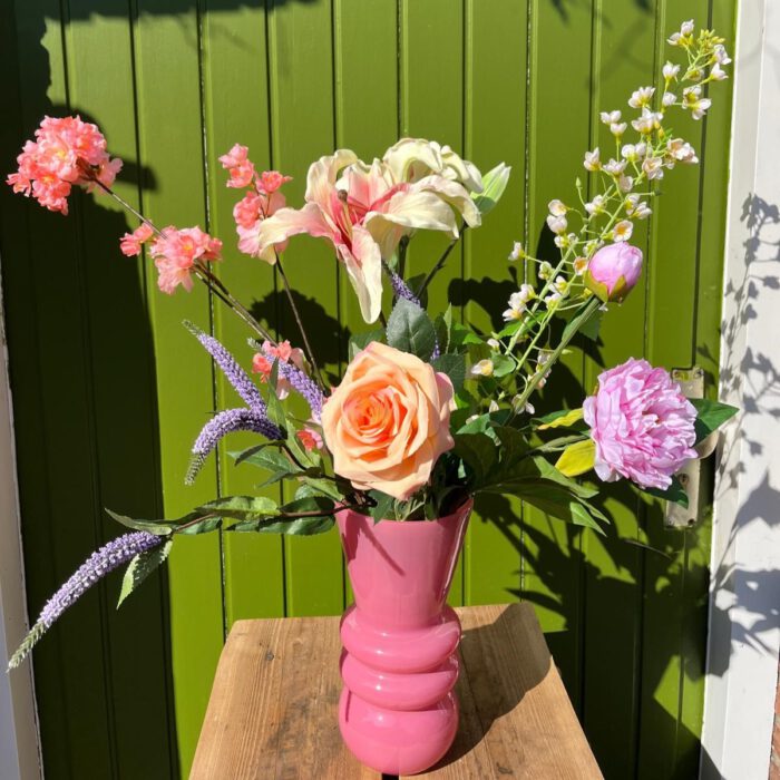Boeket van kunstbloemen in gekleurde vaas